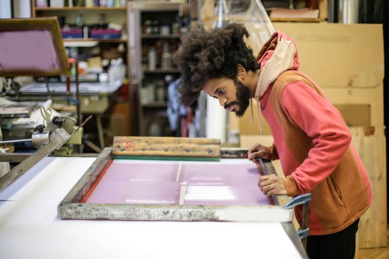 Craftsman pulling a screen print in a small print shop