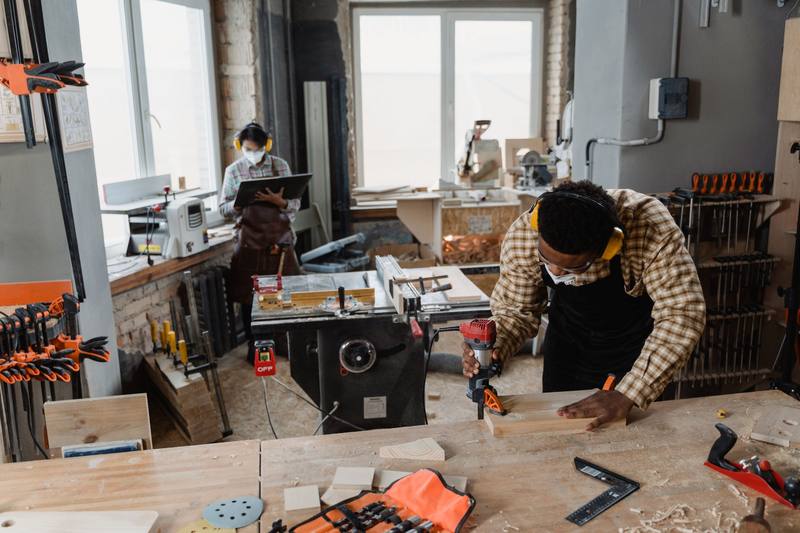 Woodworker using power tools in a bright workshop